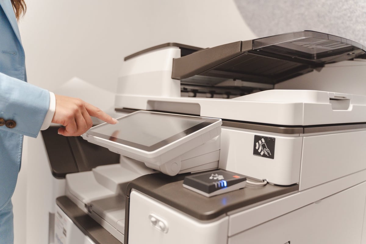 Office worker managing printing process using touchscreen of professional printer