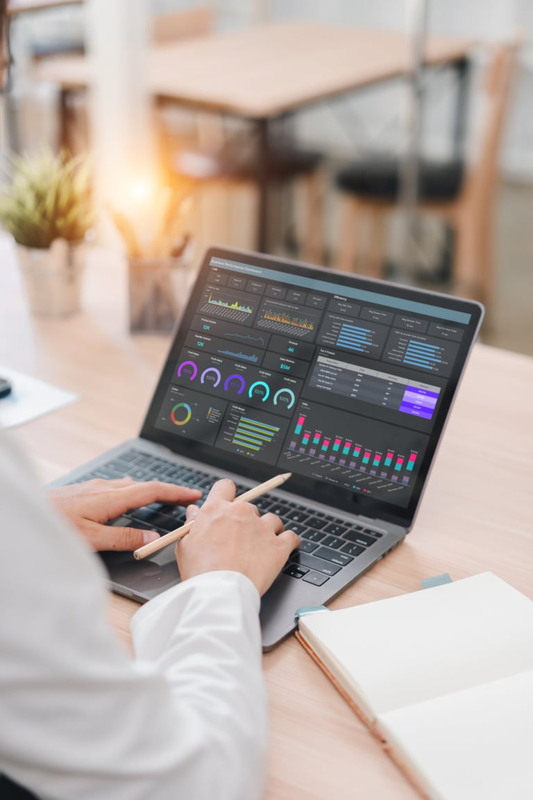 Business professional analyzing cost reports and financial data on laptop in modern corporate office